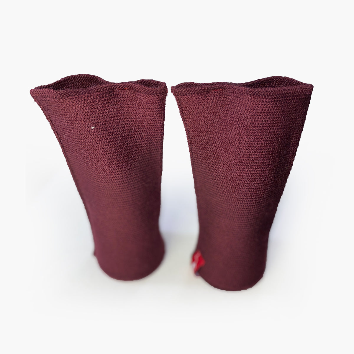 zwei Bordeauxfarbene aufrechtstehende Armstulpen mit abgenähtem Daumenloch. Man sieht das außenliegende Knötchenmuster. Innen sind die Stulpen Glatt techts gestrickt.