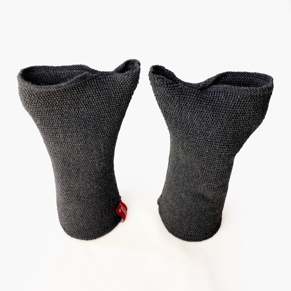 zwei Graue aufrechtstehende Armstulpen mit abgenähtem Daumenloch. Man sieht das außenliegende Knötchenmuster. Innen sind die Stulpen Glatt techts gestrickt.