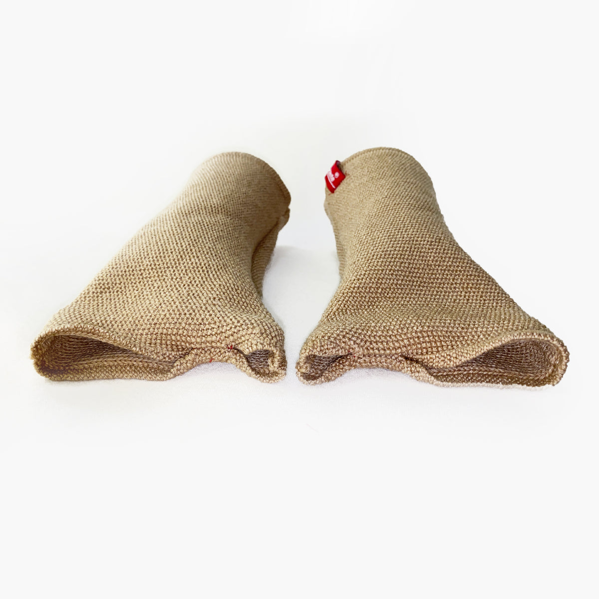zwei Beige Armstulpen mit abgenähtem Daumenloch. Man sieht das außenliegende Knötchenmuster. Innen sind die Stulpen Glatt techts gestrickt.