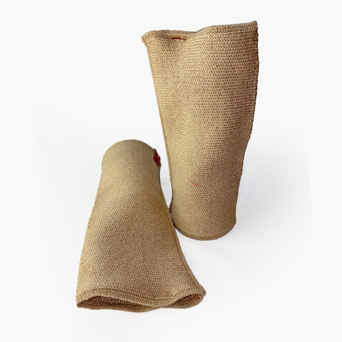zwei Beige Armstulpen mit abgenähtem Daumenloch. Man sieht das außenliegende Knötchenmuster. Innen sind die Stulpen Glatt techts gestrickt.
