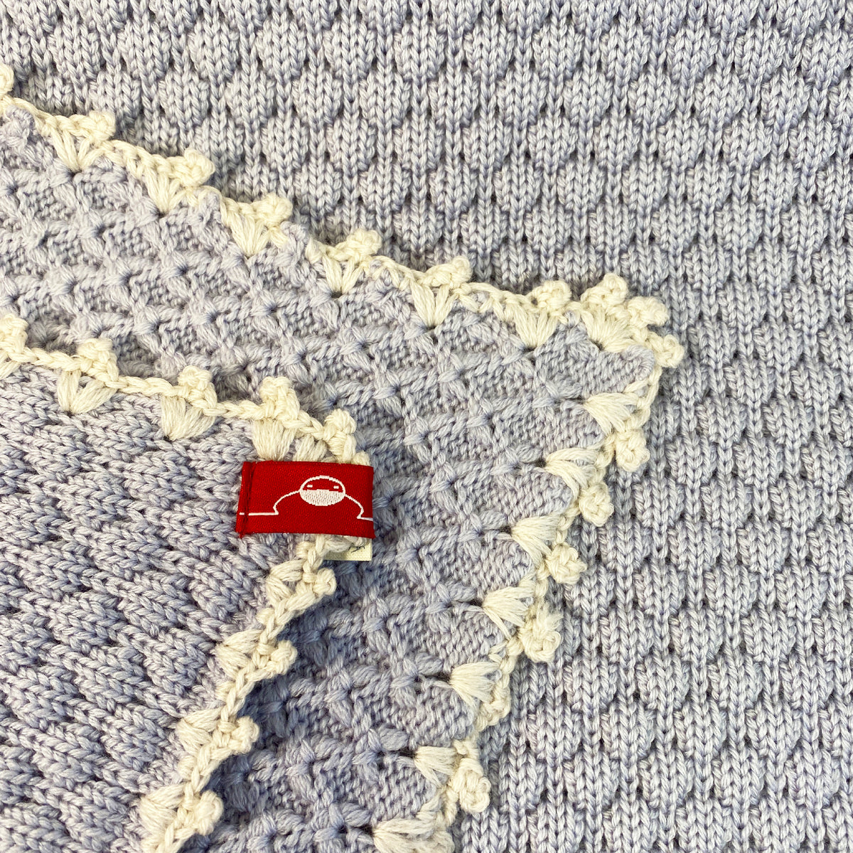 Gestrickte Babydecke aus Merinowolle im Muschelmuster mit Mäusezähnchen umhäkelt in Hellblau