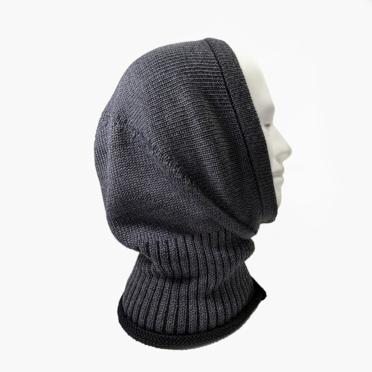 Gestrickte Mütze, die wie eine Kaputze den Kopf und Hals umhüllt. In Asphaltgrau mit Schwarzen Längstreifen um den Hals.