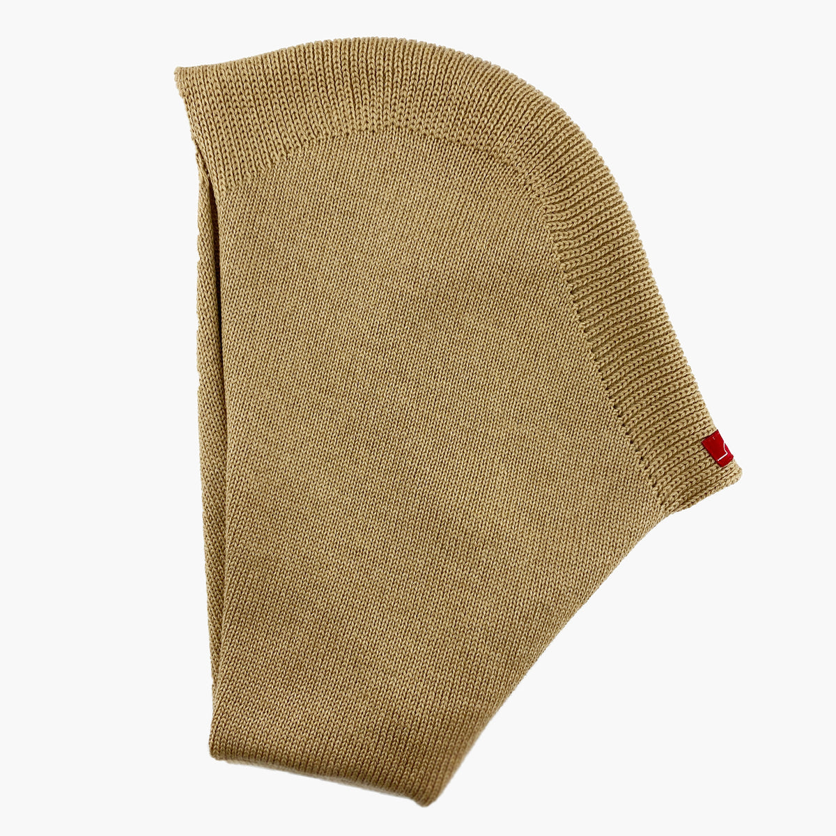 Mütze deren Form den Kopf umspielt, und auch das Kinn bedeckt, ähnlich einer geschlossenen Kapuze. Die Balaclava liegt  flach so daß man diese Kapuzenform: oben breiter zum Hals Schmal zulaufend gut sehen kann. Sie ist Beige und aus Merinowolle gestrickt.