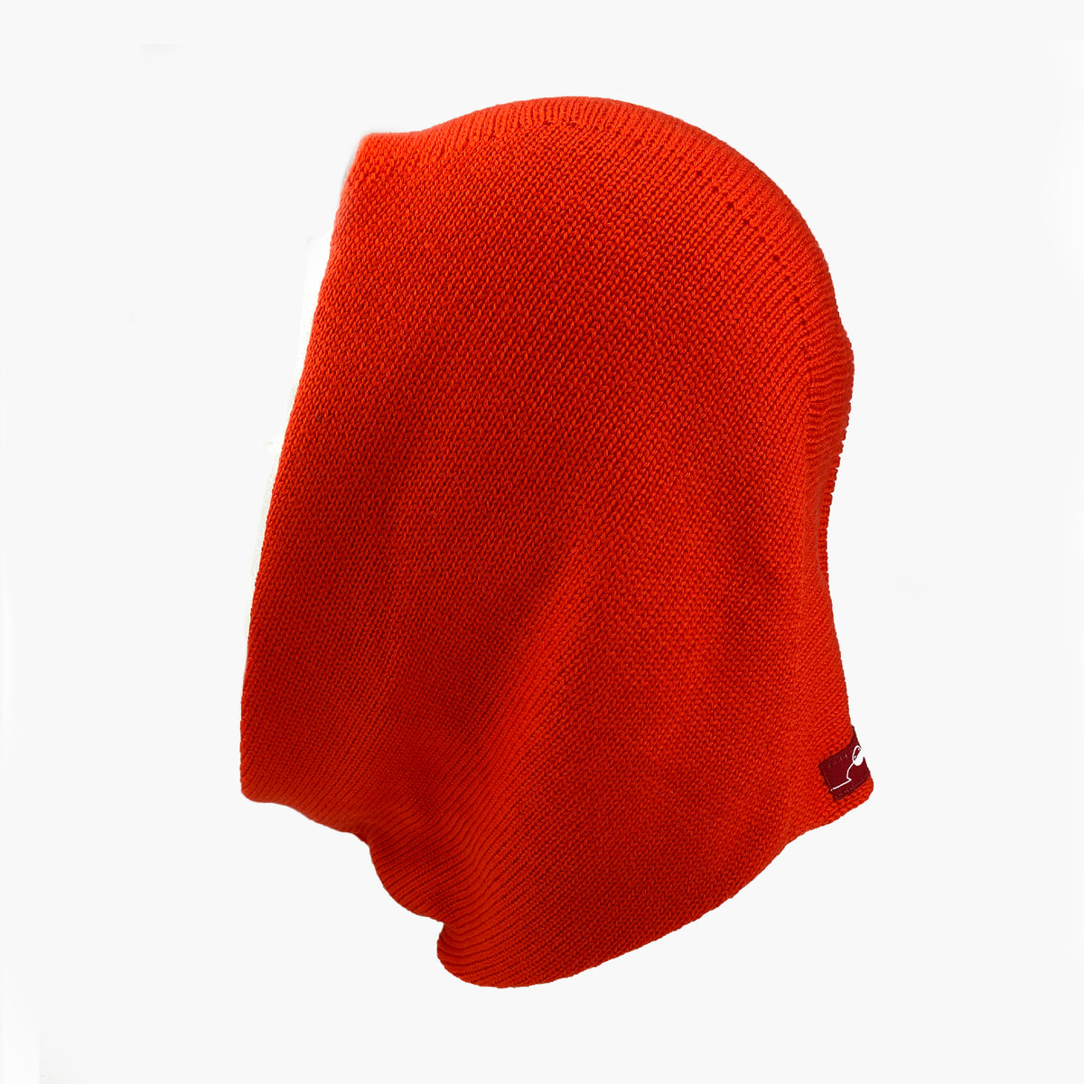 Mütze deren Form den Kopf umspielt, und auch das Kinn bedeckt, ähnlich einer geschlossenen Kapuze. Die Balaclava liegt  flach, so daß man diese Kapuzenform: oben breiter zum Hals Schmal zulaufend, gut sehen kann. Sie ist Orangerot und aus Merinowolle gestrickt.