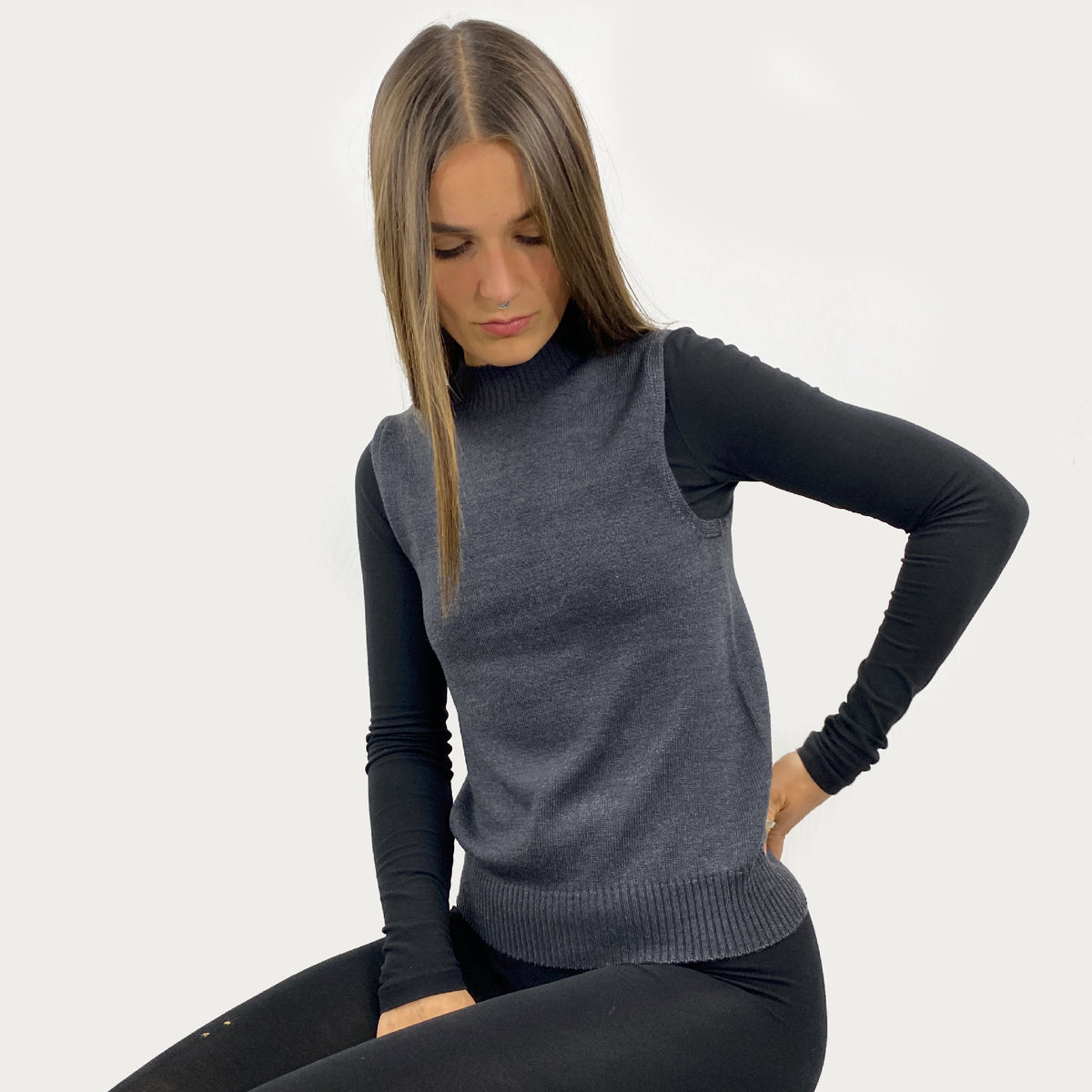 eine junge Frau mit langen Haaren trägt einen glatt gestrickten, grauen Pullunder mit hochgeschnittenem Rundhalsauschnitt im rechts/links Muster. Auch der untere Abschluß ist im rechts/links Muster.