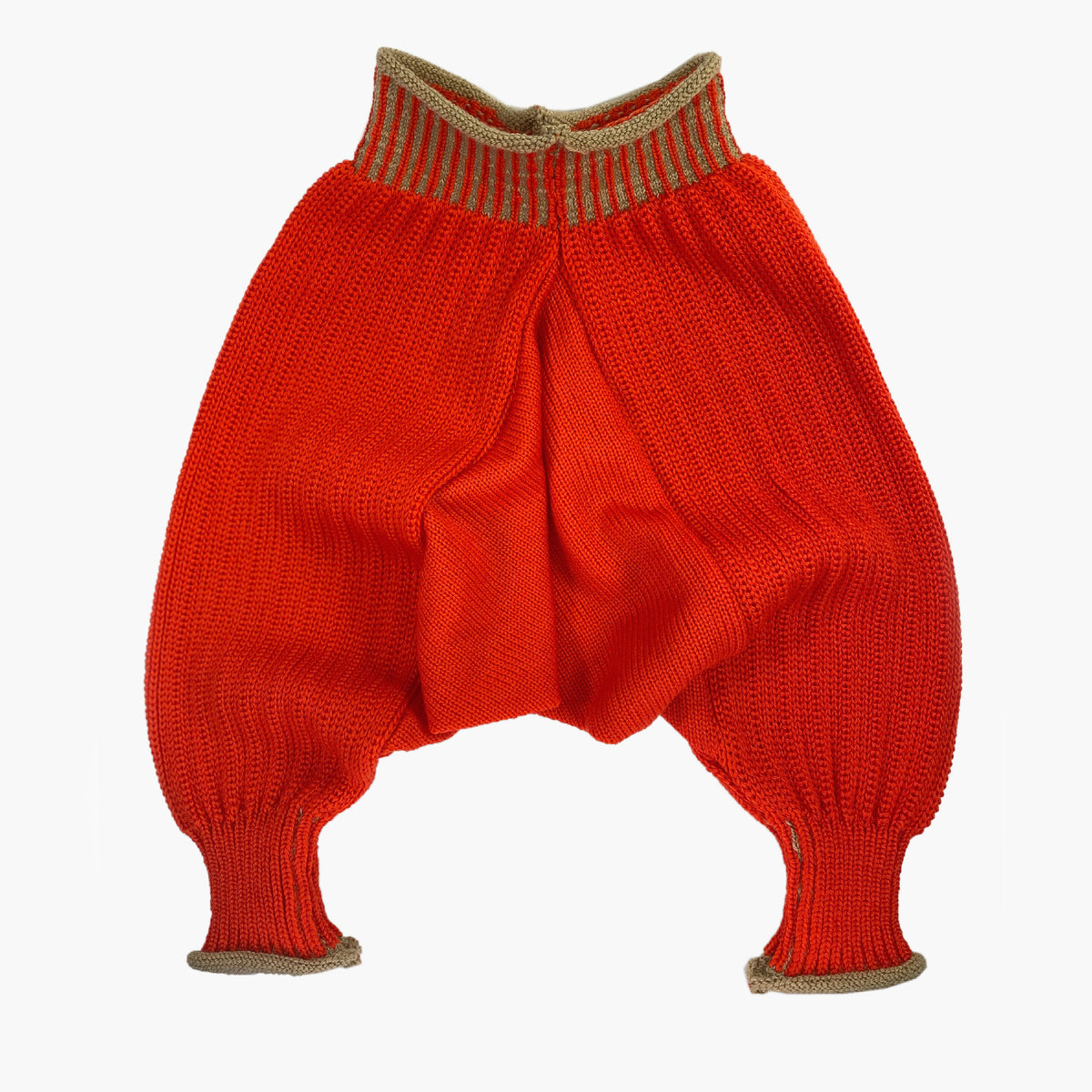 Sarouelhose auch Harems- oder Pluderhose genannt. Mit tiefgeschnittenem Schritt und extrem viel Platz für Windeln. Die Orange-Rote Wollhose ist aus feinster Bio-Merinowolle gestrickt. Sie hat enganliegende hochelastischen Bündchen, die Beige Längsstreifen haben.