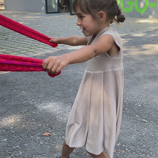 Film mit einem Mädchen, daß  ein Sommerkleid von vincente aus Tencel/Lyocell gestrickt in Beige trägt. Das Mädchen tanzt ausgelassen in einem Schulhof