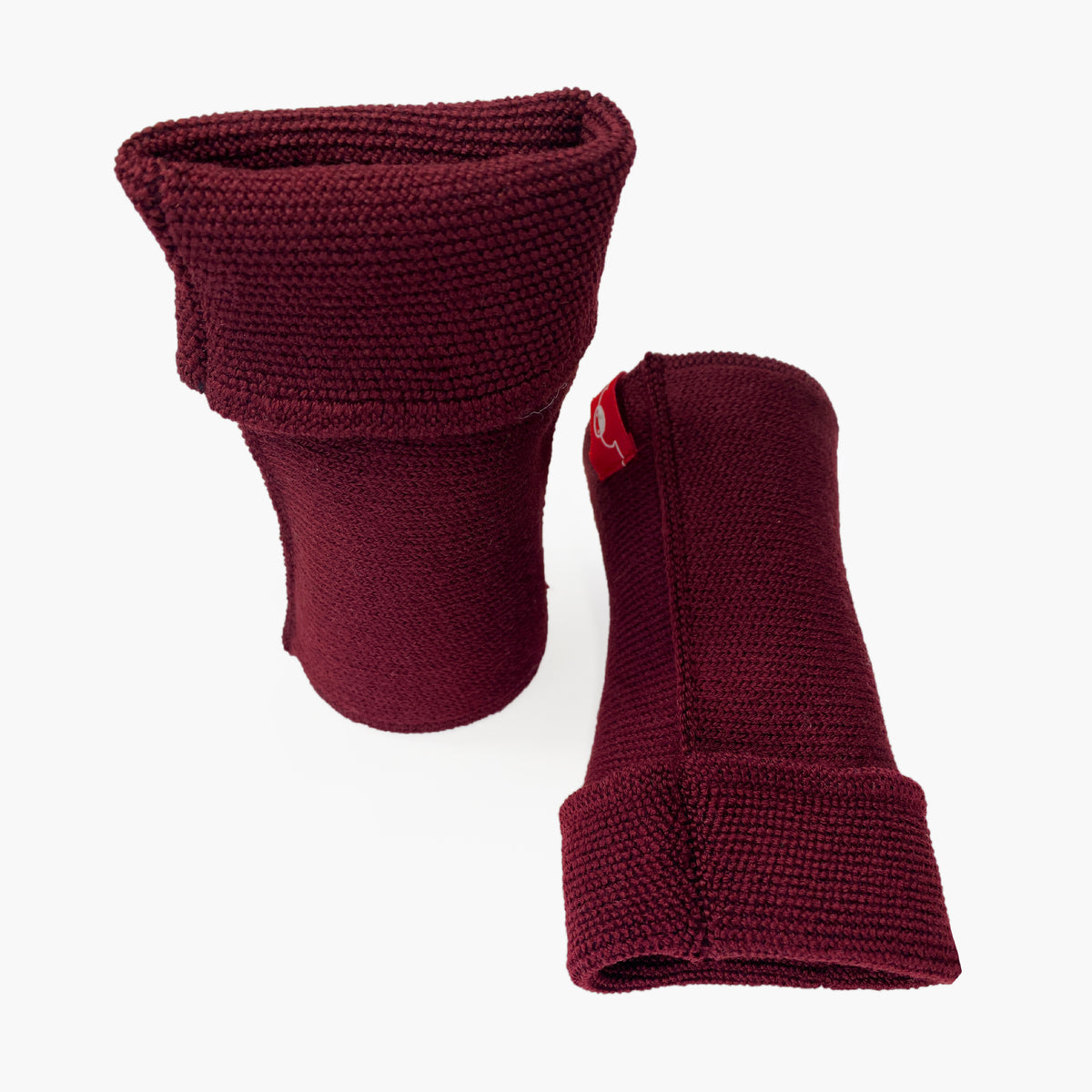 Bordeuxfarbene, aufrecht stehende Armstulpen. Man sieht das außenliegende Glatt Rechts Muster. Innen sind die Stulpen in einem Feinen Knötchenmuster gestrickt, man kann sie auch Innsideout tragen