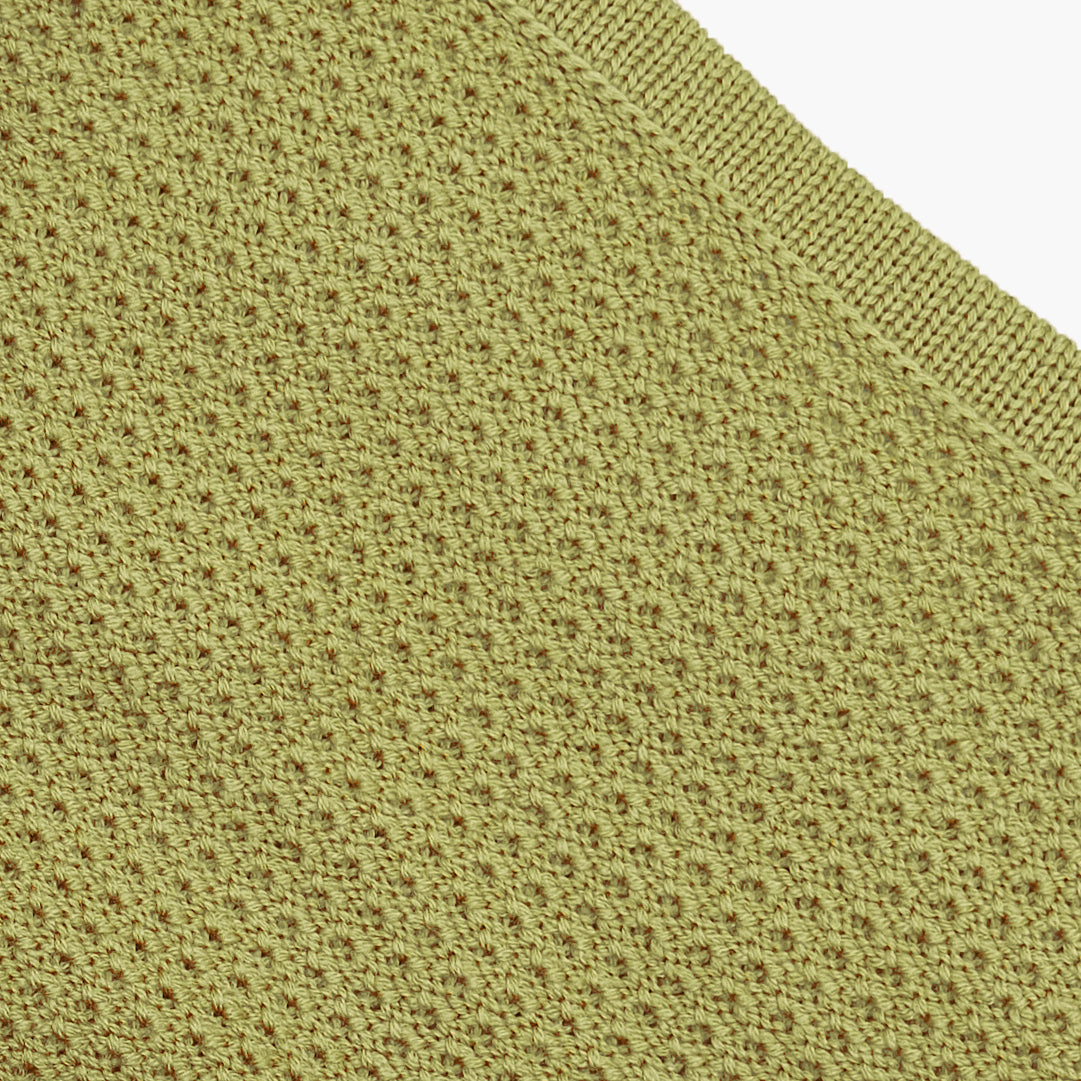 Closeup der Strickstrucktur der Rückseite der gestrickten Baydecke. Das Fangpatentmuster sieht wie kleine Bögen aus die sich endlos wiederholen. Die Wolle ist Matcha Grün
