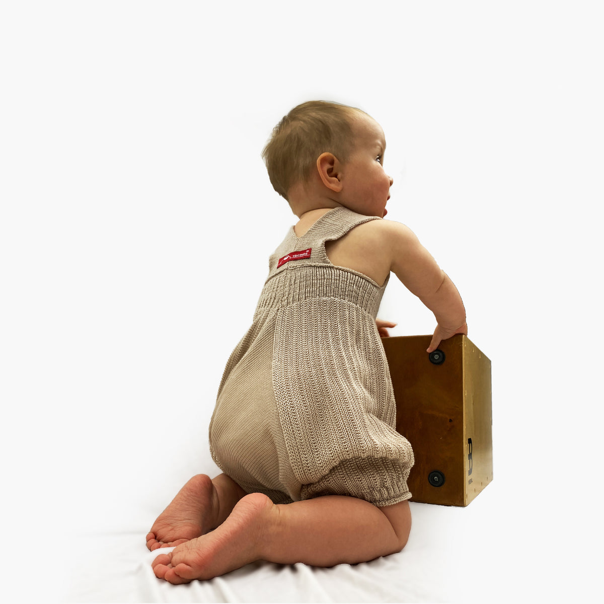 Ein kniendes Baby trägt eine gestrickte kurze Sommerhose aus Tencel/Lyocell mit tiefen Schritt und viel Platz für Windeln. Die Hose von vincente hat hochelastische Hosenträger  und ist Beige/Champagnerfarben