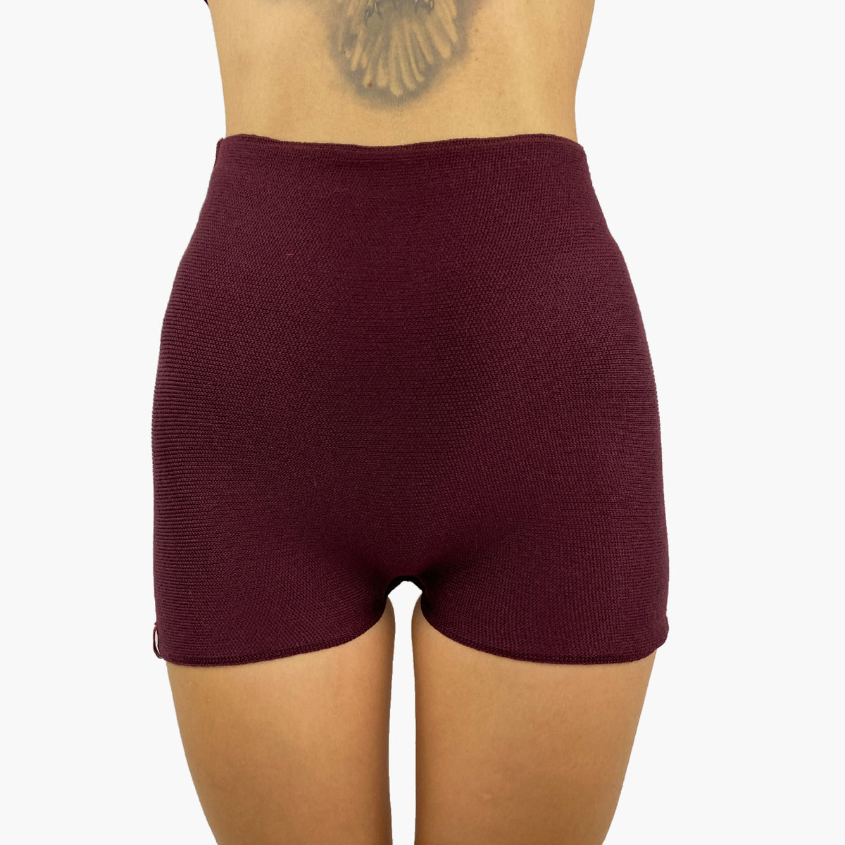 ein Model trägt eine Bordeauxrote Wollunterhose mit angeschnittenem kurzen Bein. Die Hotpants geht bis zur Taille.