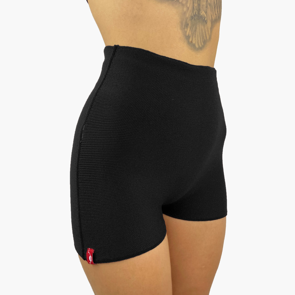 ein Model trägt eine Schwarze Wollunterhose mit angeschnittenem kurzen Bein. Die Hotpants geht bis zur Taille.