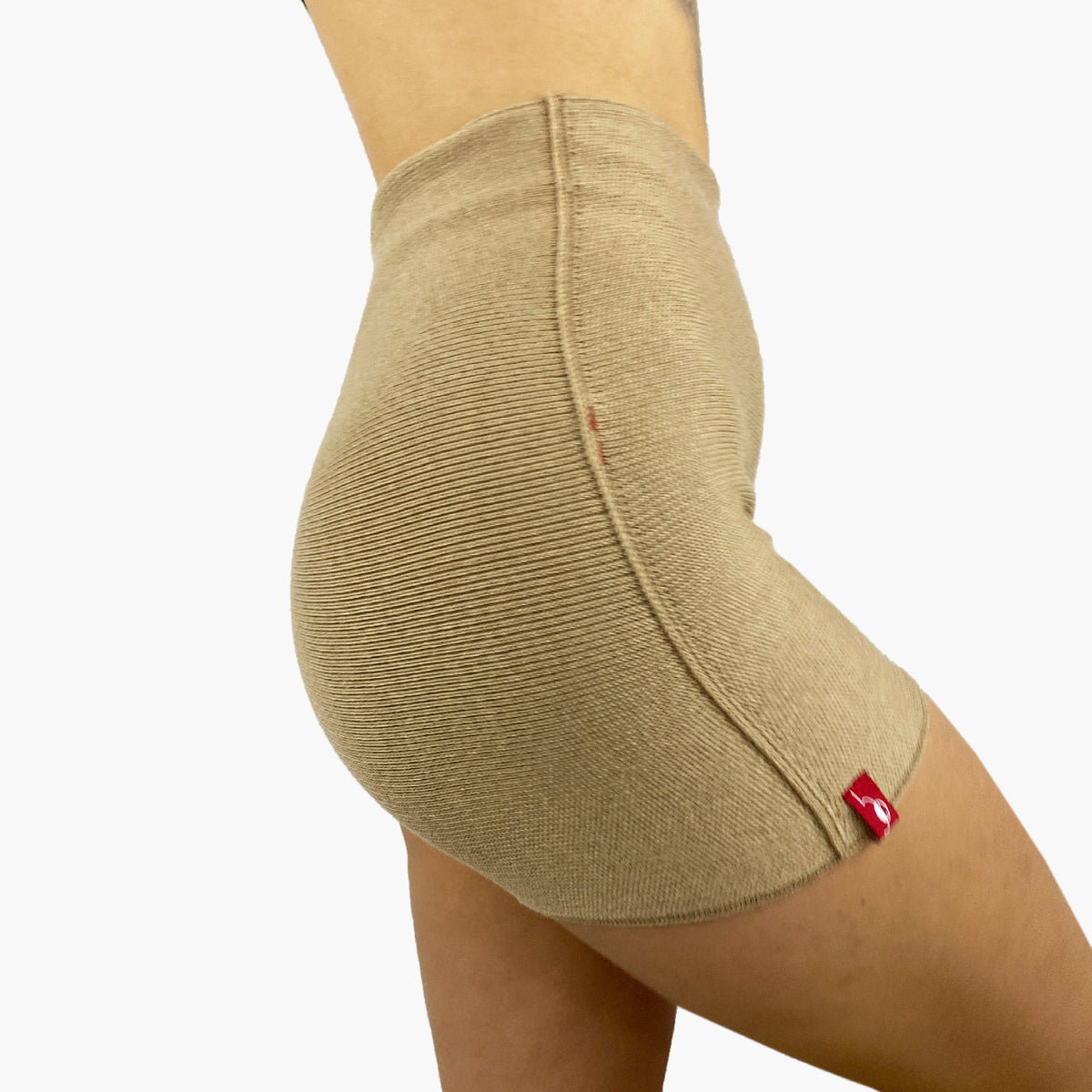 ein Model trägt eine Beige Wollunterhose mit angeschnittenem kurzen Bein. Die Hotpants geht bis zur Taille. Man sieht die Seitenansicht mit einer Häkelnaht und dem roten vincente-Label