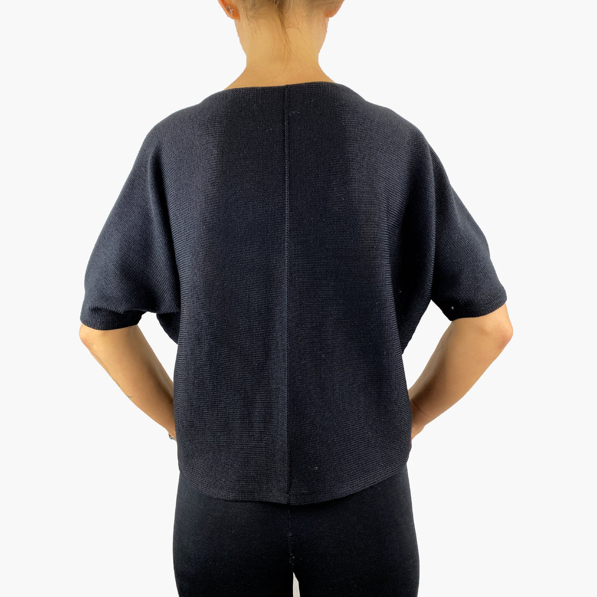Schwarzer quer gestrickterPullover mit kurzen, angeschnittenen Ärmeln ähnlich wie beim T-Shirt. Mit kleiner Falte am Armende. In der hinteren Mitte, die man hier sieht ist eine längsverlaufende Häkelnaht.