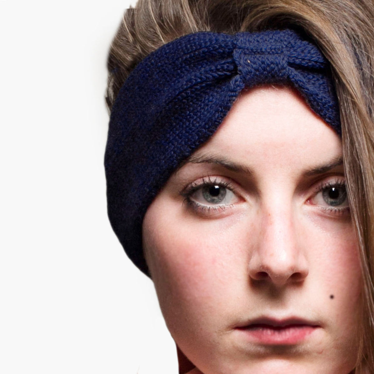 Eine Junge Frau trägt ein Royalblaues, gestricktes Stirnband mit einer kleinen Schlaufe