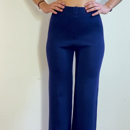 Ein Model dreht sich langsam im Kreis und präsentiert eine Strick-Hose in Royalblau mit ausgestelltem Bein.