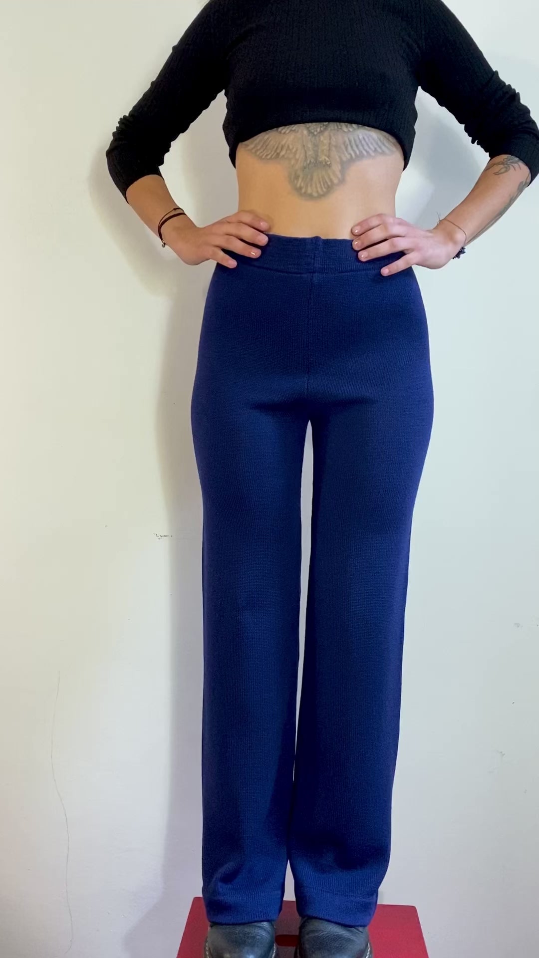 Ein Model dreht sich langsam im Kreis und präsentiert eine Strick-Hose in Royalblau mit ausgestelltem Bein.