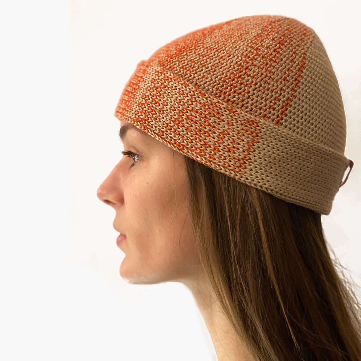 Eine Frau trägt eine Beanie-Mütze, mit Farbverlauf der sich in verschiedenen Karamel und Orange Kobinationen ändert.