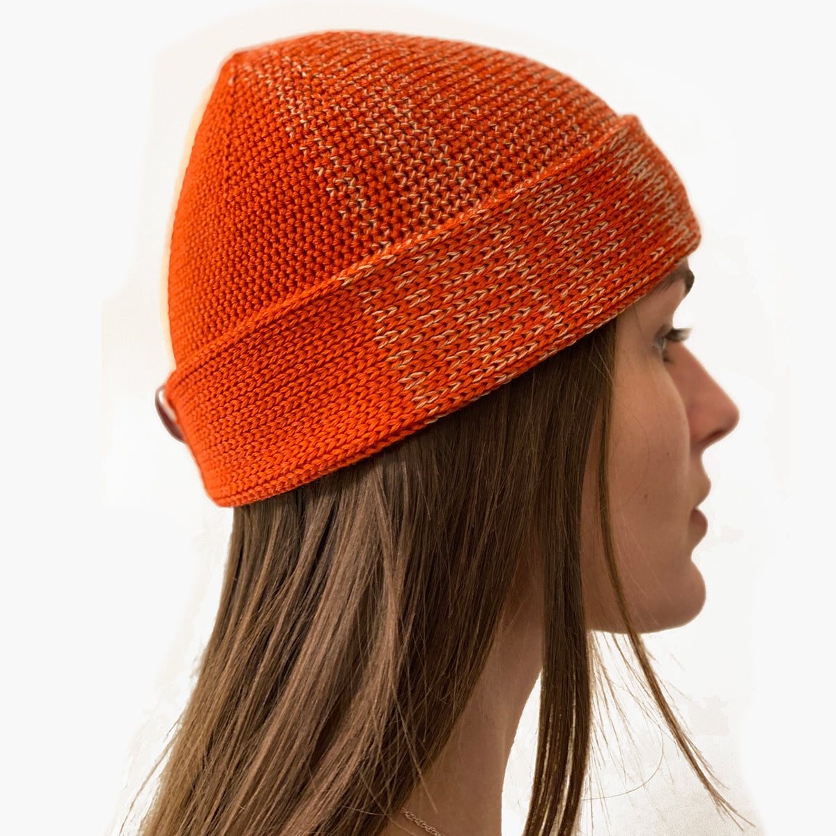 Eine Frau trägt eine Beanie-Mütze, mit Farbverlauf der sich in verschiedenen Karamel und Orange Kobinationen ändert.