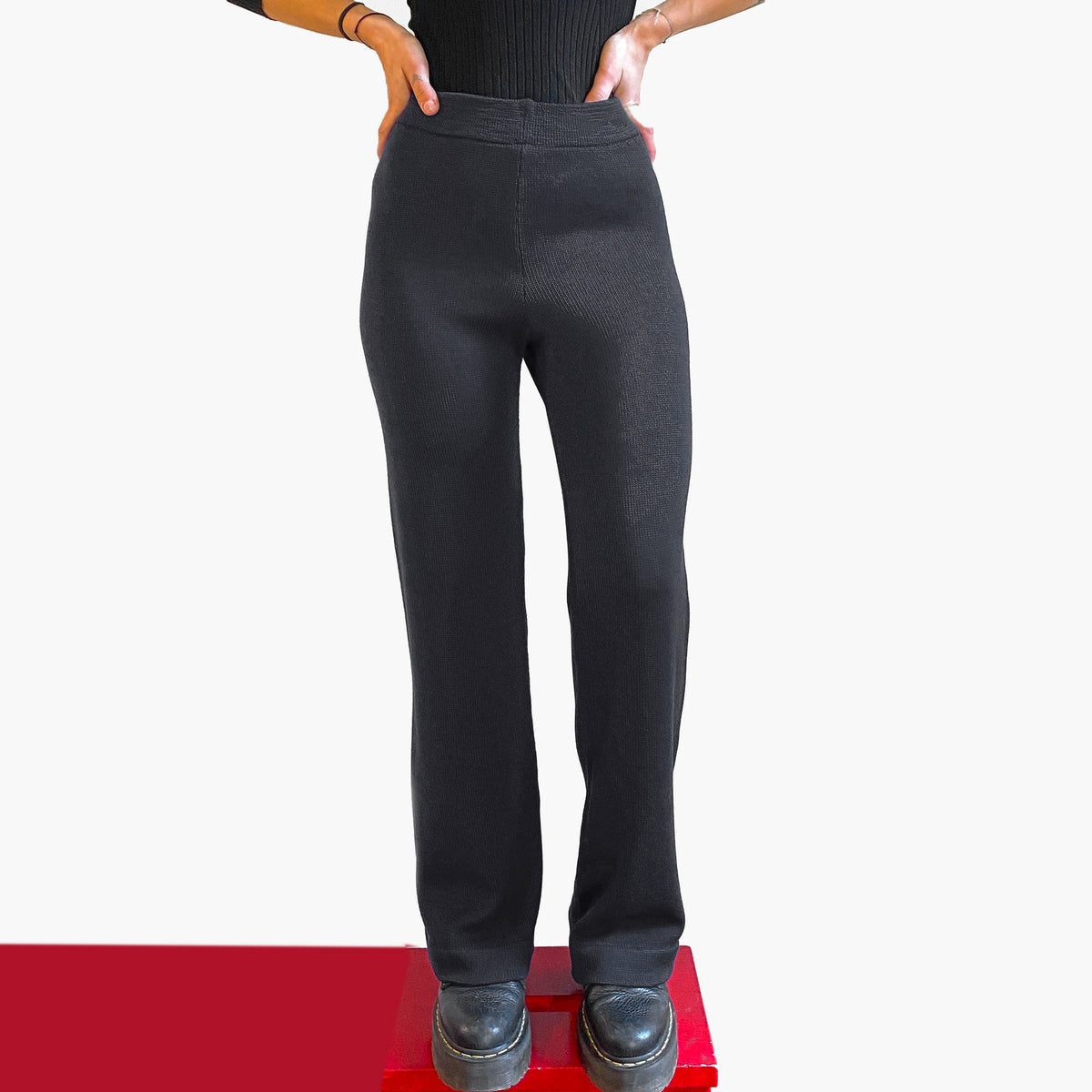 Ein Model vom Bauchnabel abwärts trägt eine Strick-Hose in Schwarz mit ausgestelltem Bein.