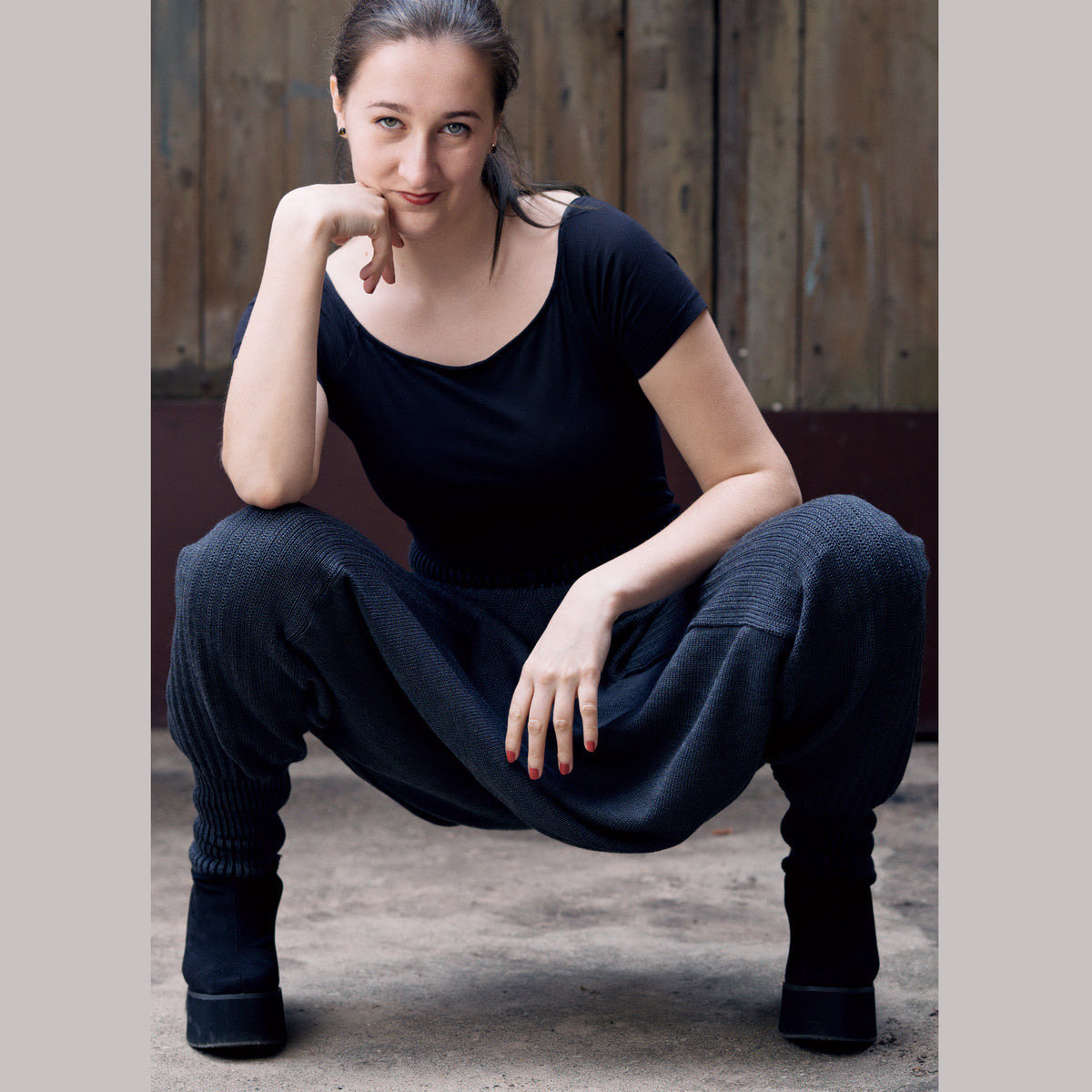 Eine Frau sitzt in der Hocke und trägt eine weite gestrickte Sarouelhose mit tiefem Schritt und eng anliegenden Bündchen.