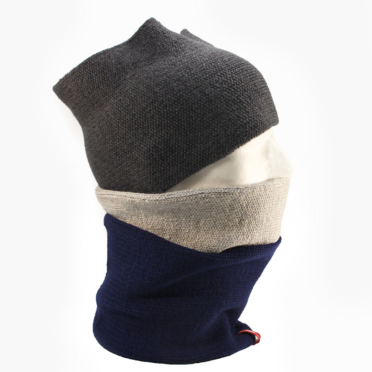 Auf einen Männerpuppenkopf sind 3 gestrickte Loops trapiert. Ein dunkelgrauer über die Stirn ein Silbergrauer über den Mund und ein Royalblauer über den Hals.
