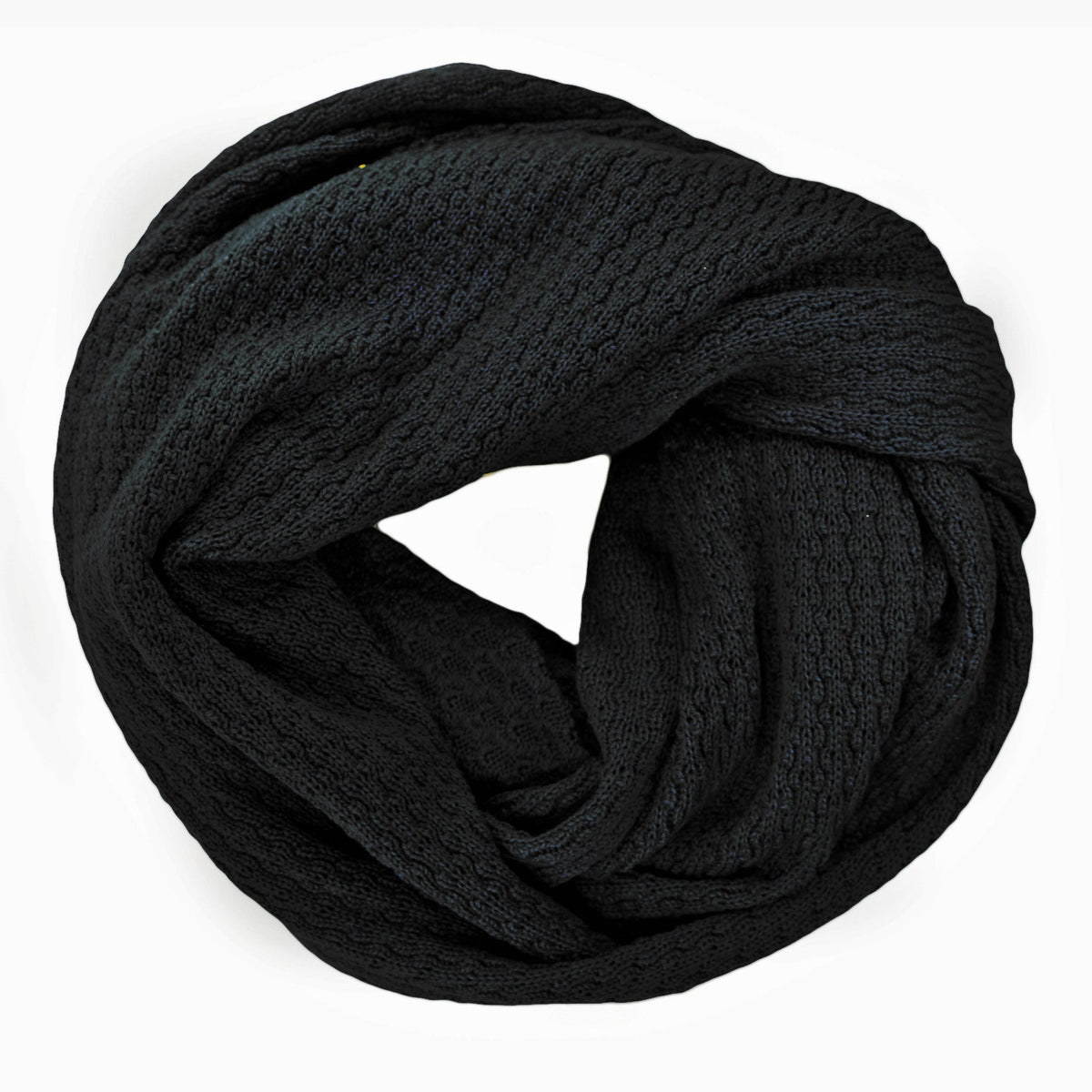 Schwarzer, gestrickter Loop im Fangpatentmuster. Eine Seite sieht glatt rechts mit kleinen Wellen gestrickt aus, die andere Seite sieht aus wie kleine Muscheln. Der Wollschal ist zu einem Haufen drapiert, so sieht man den weichen Fall.