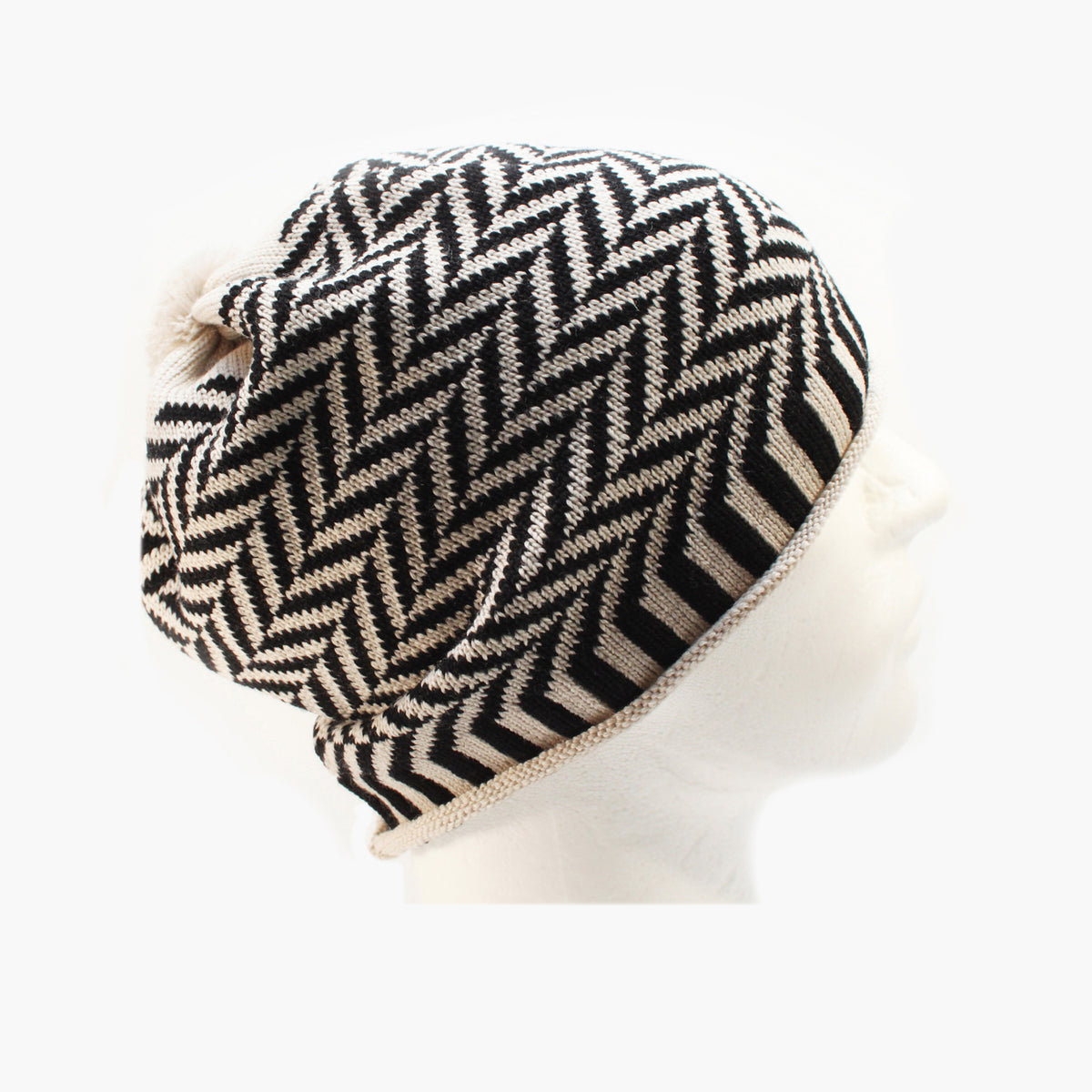 Schwarz/Weiße  Beanie-Mütze aus Merinowolle mit längs gestreiften elastischem Bündchen. Die Mütze ist im klassichem Fischgrätmuster gestrickt und hat eine kleine unauffällige Bommel.